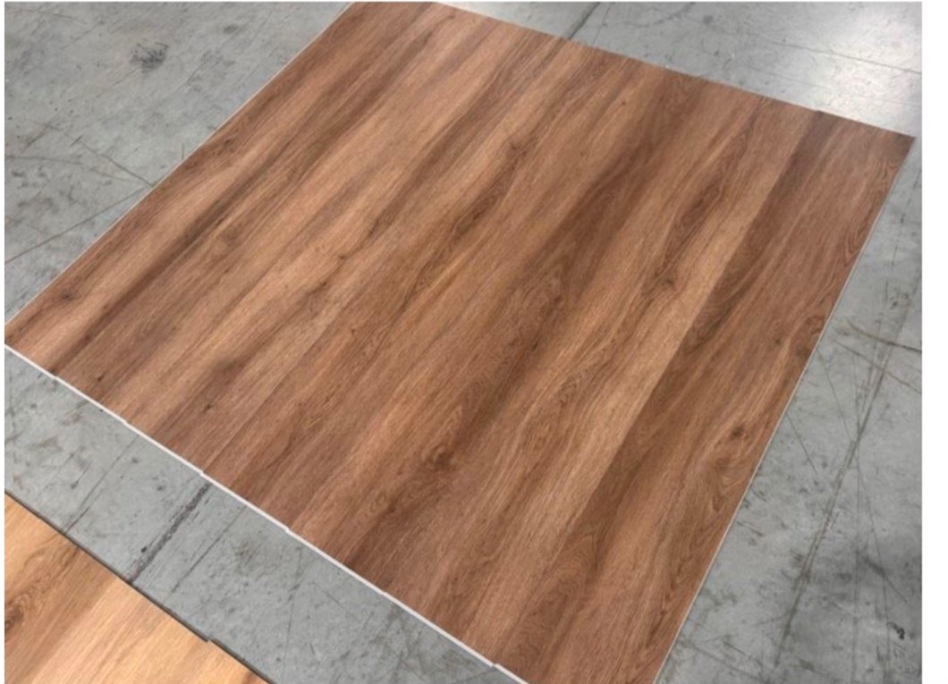 Amber Walnut waterproof LVP planks clicked together on the warehouse floor, showing warm reddish-brown grain