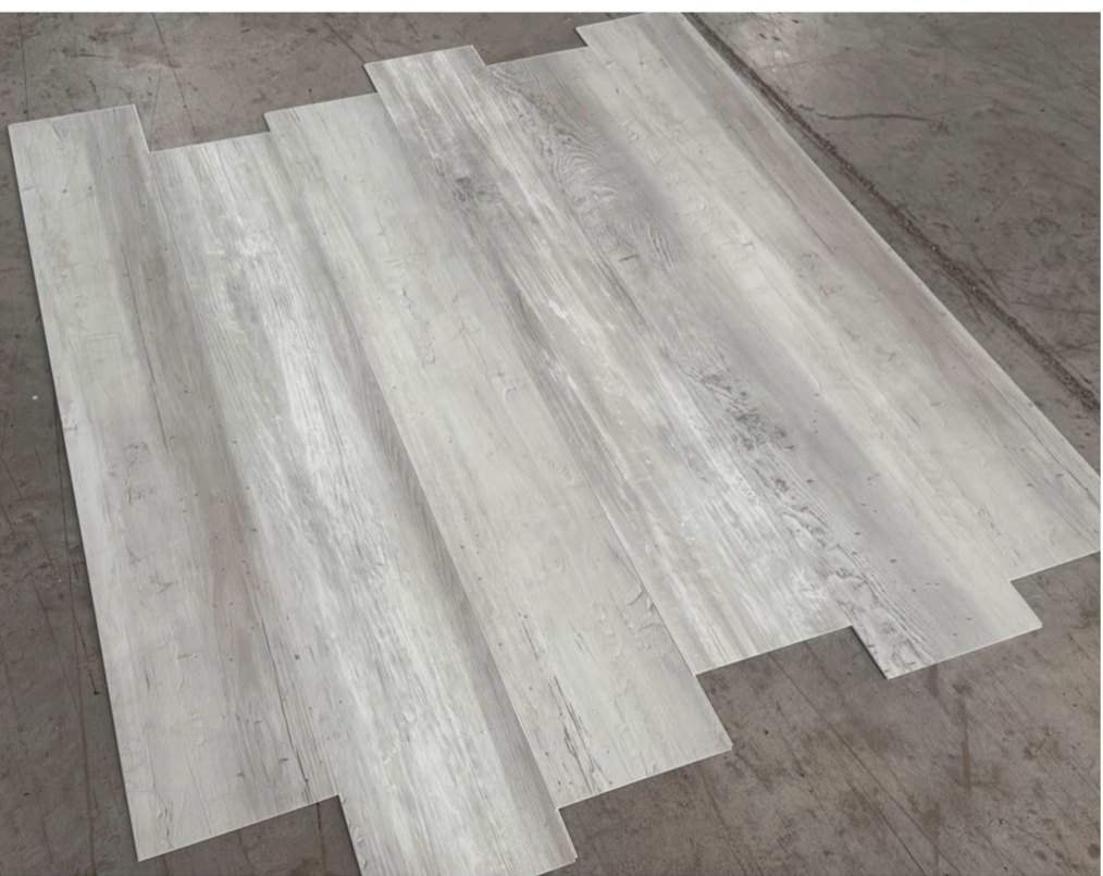 Coastal Whitewash waterproof LVP planks laid out, showing weathered gray-white reclaimed pine grain